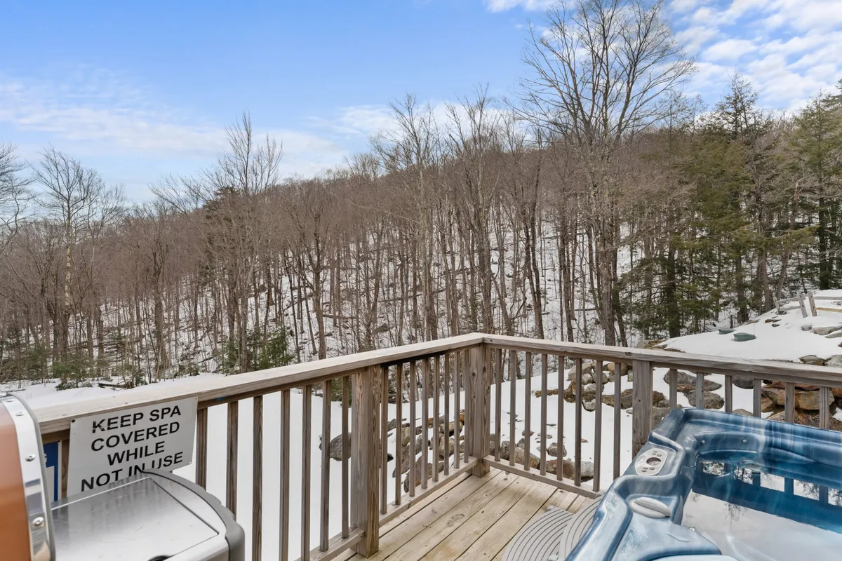 A close-up exterior shot of the hot tub, framed by a snow-covered landscape and wooden railings. The scene conveys peace and privacy, with the hot tub as the clear focal point for relaxation after outdoor activities.