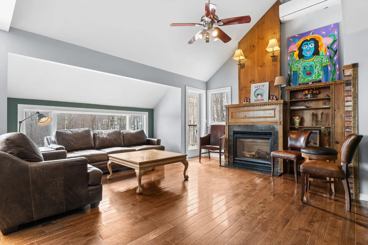 The hero image showcases a warm, sunlit living room featuring a plush sofa and comfortable chairs arranged around a crackling fireplace. Inviting wooden accents, tasteful artwork, and a sturdy coffee table create a perfect gathering space for relaxation, conversation, and unwinding after a day on the slopes.