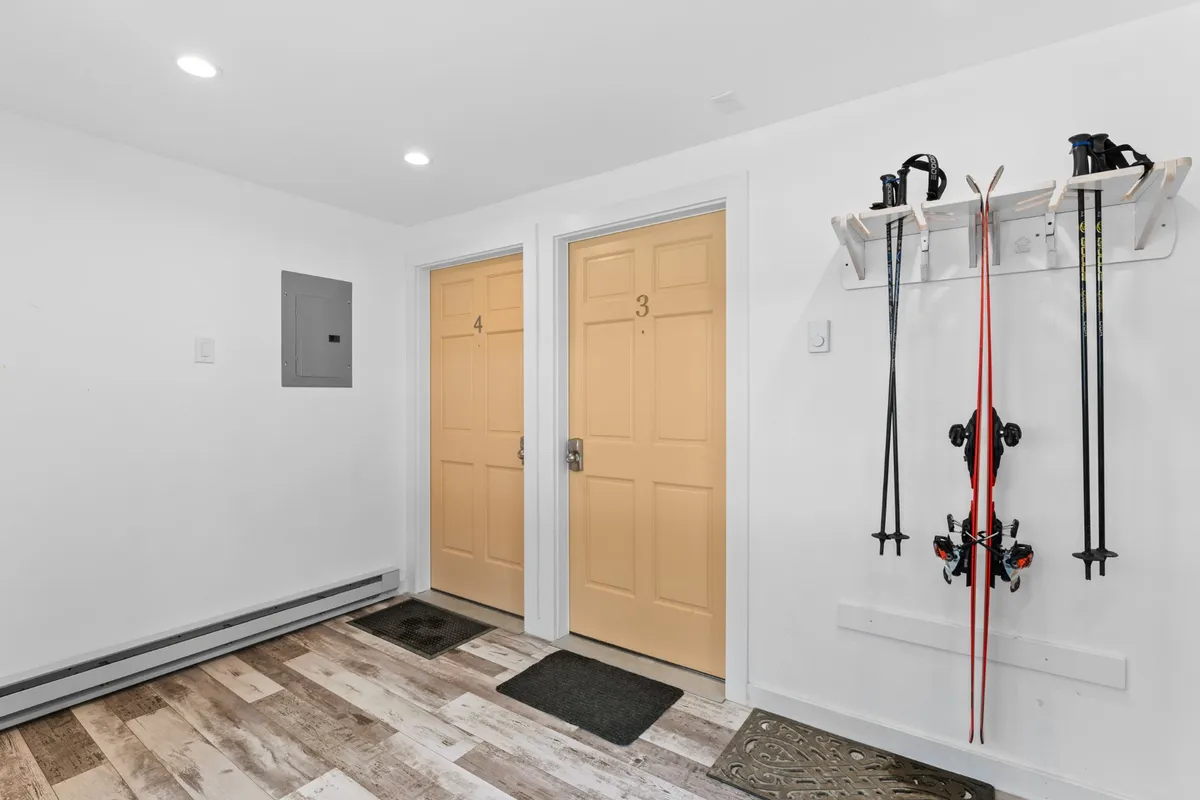 A functional mudroom area with numbered doors, ski equipment mounted on the wall, and warm wooden flooring. The space is inviting and practical, ideal for gearing up for mountain adventures or keeping belongings organized and clutter-free.